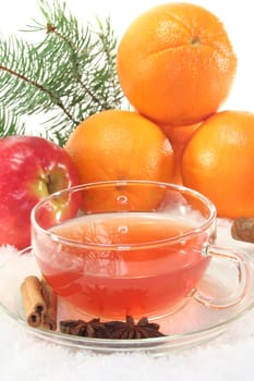 Winter tea with fresh apples and oranges, pine branch and spices in the snow