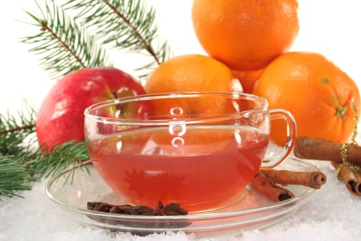 Winter tea with fresh apples and oranges, pine branch and spices in the snow