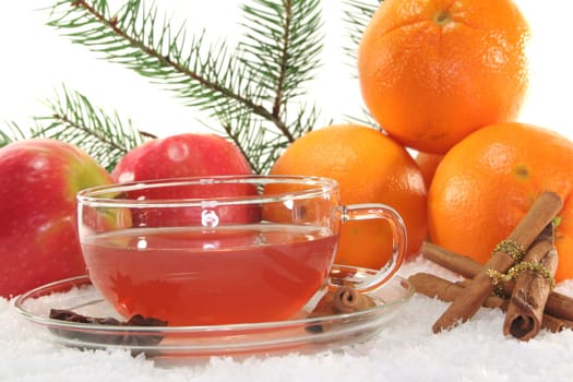 Winter tea with fresh apples and oranges, pine branch and spices in the snow