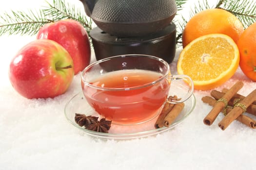 Winter tea with fresh apples and oranges, pine branch and spices in the snow