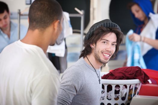 Young handsome man with his friend smiles in the laundromat 