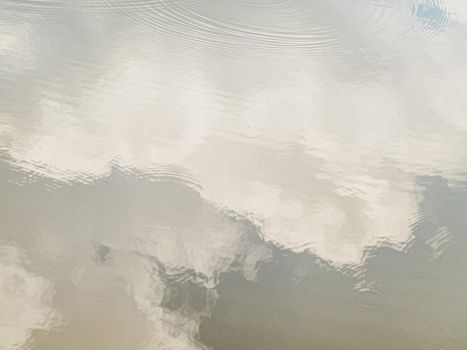 White clouds reflection in a river with small ripples