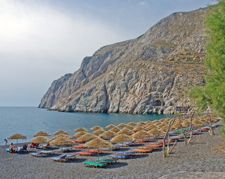 The Headland of Kamari Beach Santorini with thatched umbrellas