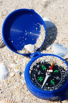 Dark blue compass on sand
