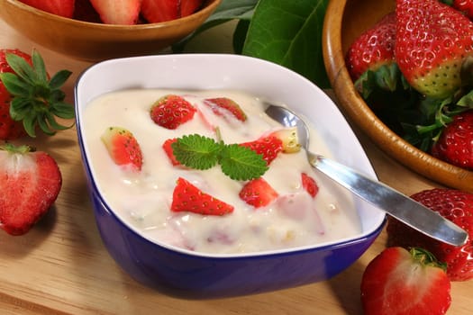 Strawberry yogurt with fresh strawberries on a wooden board