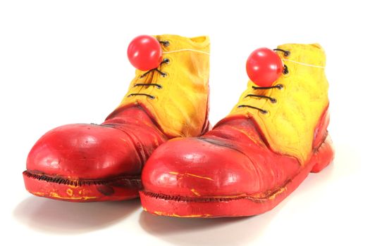 red and yellow clown shoes with red clown noses on white background