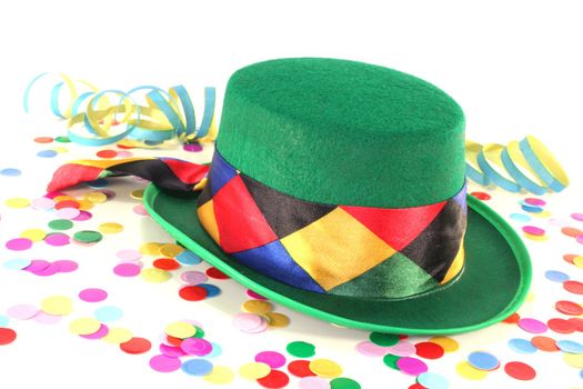 Carnival hat with colorful confetti and streamers on white background