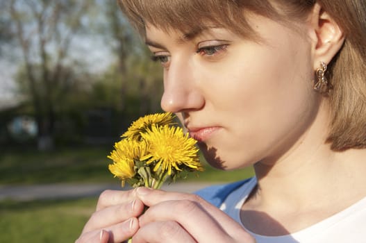 The girl enjoys a smell dandelions