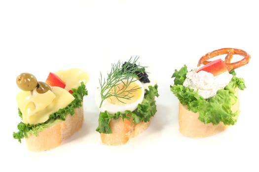 Canape with lettuce, cheese, sausage, cream cheese and eggs on a white background