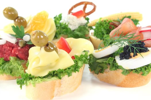 Canape with lettuce, cheese, sausage, cream cheese and eggs on a white background
