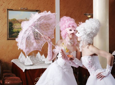 Two girls in wedding dresses and masks
