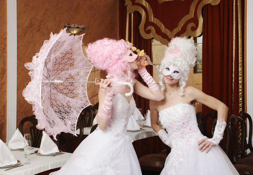 Two girls in wedding dresses and masks
