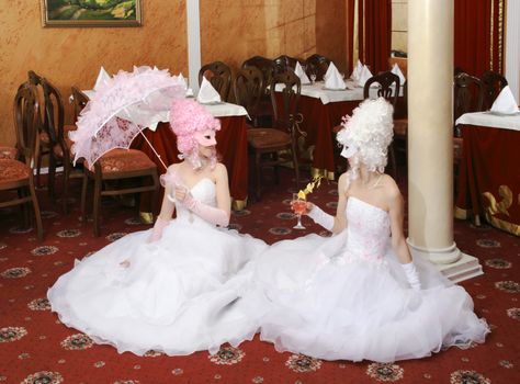 Two girls in wedding dresses and masks
