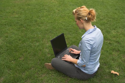 woman sitting on grass and working with laptop computer