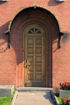 Old wooden door with metal moulding in a red brick wall