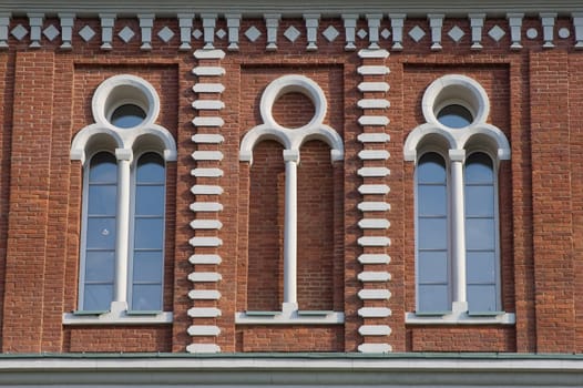 Three high glassed white-framed windows in a red brick wall