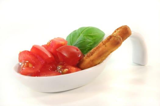 Grissini with tomato pieces and basil in appetizer spoons on white background