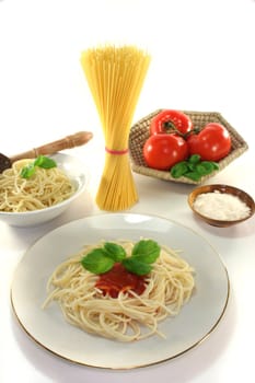 Spaghetti with tomato sauce and fresh basil on a white background