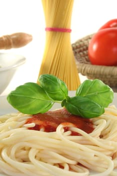 Spaghetti with tomato sauce and fresh basil on a white background