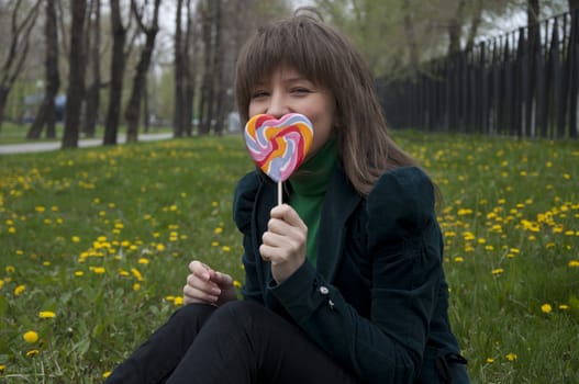 young girl with candy sitting on the grass in the park