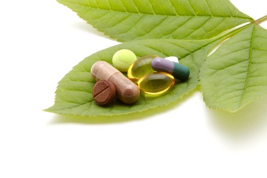 vitamins, tablets and pills on green leaf