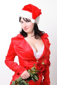 Portrait of a beautiful young woman in a red suit and hat of Santa Claus with red roses on the grey background
