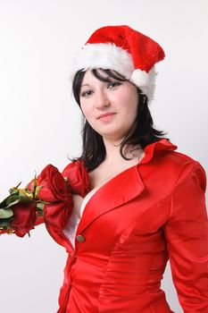 Portrait of a beautiful young woman in a red suit and hat of Santa Claus with red roses on the white background
