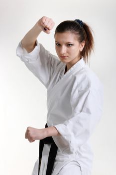 Karate. Young girl in a kimono with a white background
