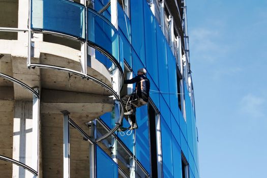 Builder fixing glass on tall building