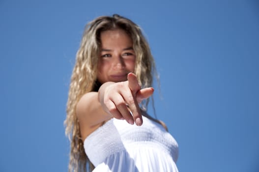 Portrait of the young woman pointing a finger against the blue sky