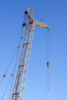 Yellow building crane against a clear blue sky.