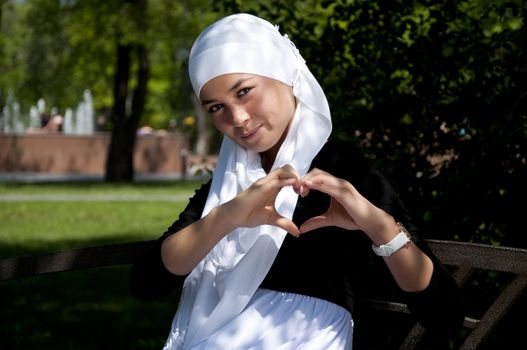 Portrait of young woman in park with a white scarf on a head