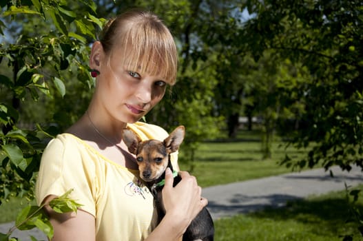 The girl holds a small dog on hands