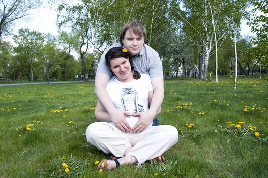 man hugs pregnant woman in the park