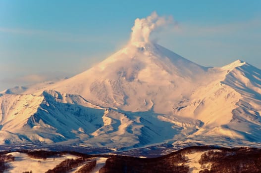 Beautiful snow-covered volcano a letting out smoke from a crater