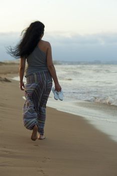 Hispanic woman enjoying a barefood walk on the beach