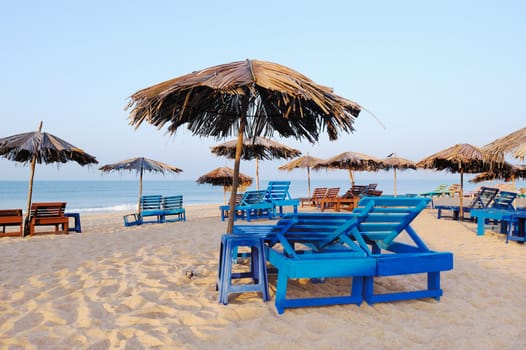 Exotic lean-to of palm leaves and deck-chairs on tropical beach