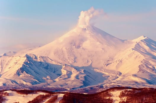 Beautiful snow-covered volcano a letting out smoke from a crater