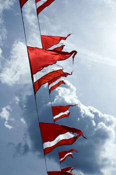 Red-white triangular ship flags flap in the breeze against a cloudy sky