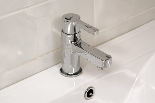 Modern metallic faucet with water drops