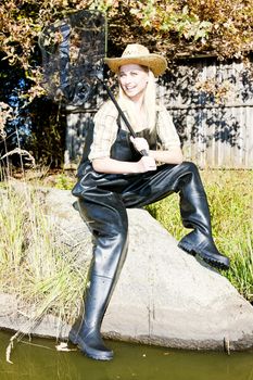 fisher woman with landing net sitting on stone