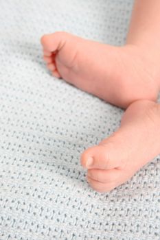 Baby feet on a blue woolen blanket