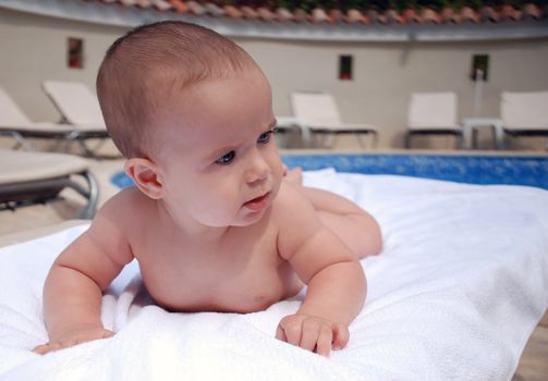 baby lying on lounger on background of pool and  loungers