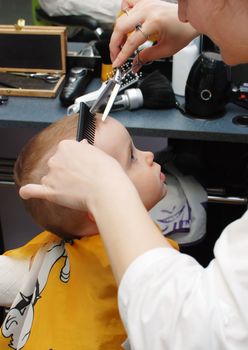 Haircutting one year boy in the hairdressing saloon