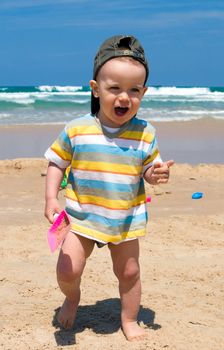 Happy one year old boy on beach