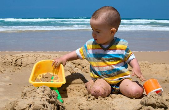 One year old child building sand castle on the beach