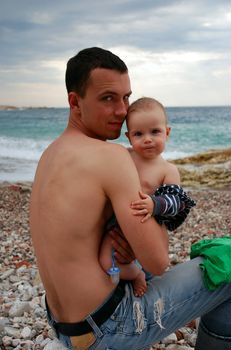 Father and son sitting near sea