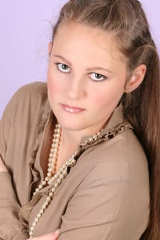 Beautiful teenage female against purple background, wearing pearls