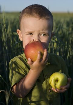Portrait of little boy biting red apple