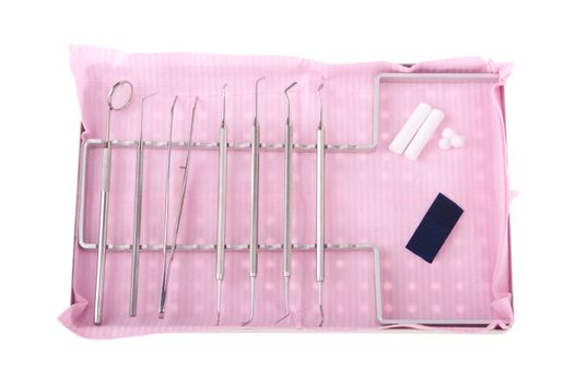 dentistry kit in a tray on pink bib (surgery instruments, articulation paper, cotton rolls and wools)